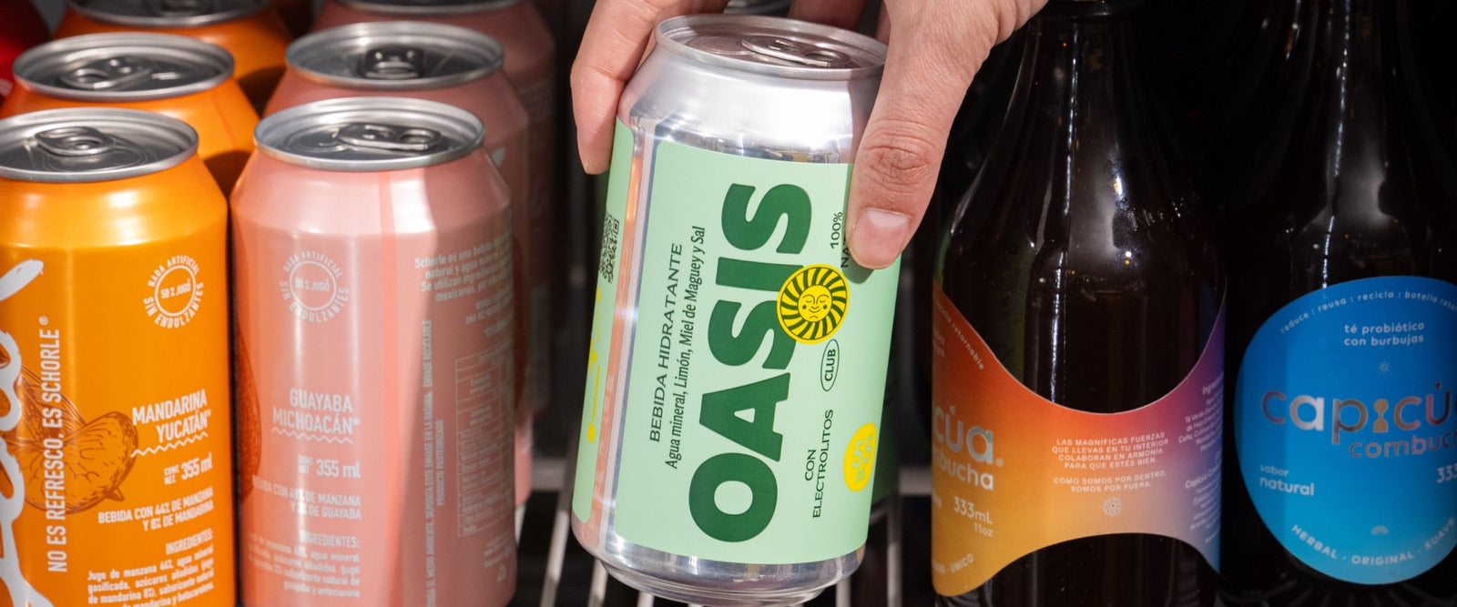 Mano tomando una lata de Oasis del refrigerador